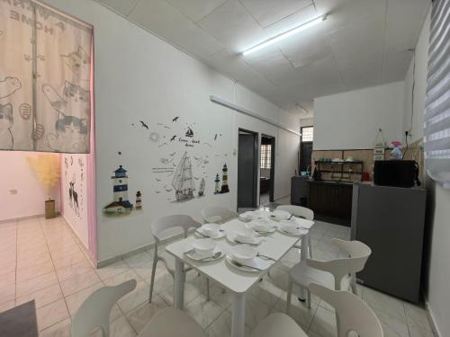 a dining room with a white table and white chairs at Padang Serai Harmoni Homestay in Padang Serai