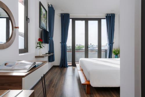 a bedroom with blue curtains and a bed and a window at Sunora Villa Hoi An in Hoi An