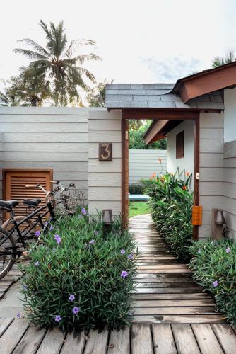 a wooden walkway leading to a house with flowers at Belukar Villas in Gili Trawangan