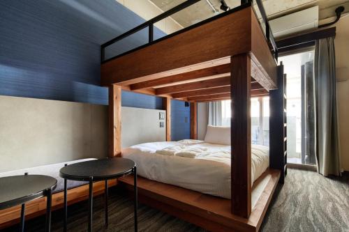 a bedroom with a bunk bed with two tables at BbyC Hotel 那覇 レンタカー付ホテル in Naha