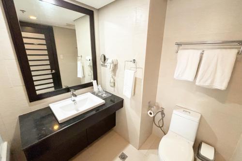 a bathroom with a sink and a toilet and a mirror at The Muse Hotel Boracay in Boracay