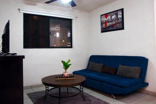 a living room with a blue couch and a table at Departamento en Guadalajara in Guadalajara