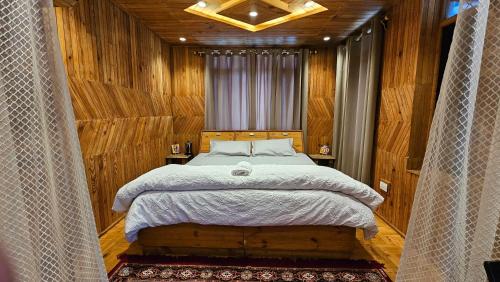 a bedroom with a large bed with wooden walls at Khwabgaah Manali in Manāli