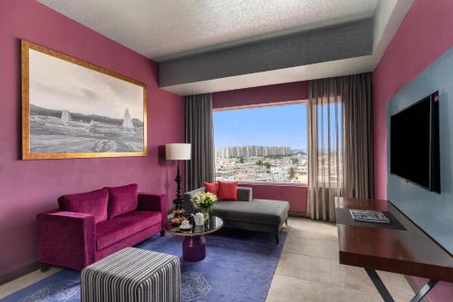 a living room with pink walls and a large window at Grand Mercure Bengaluru at Gopalan Mall - An Accor Brand in Bengaluru