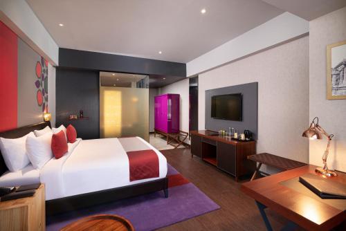 a bedroom with a bed and a desk and a tv at Grand Mercure Bengaluru at Gopalan Mall - An Accor Brand in Bengaluru