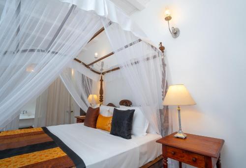a bedroom with a canopy bed with white curtains at Adigars Manor in Kandy