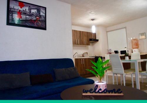a living room with a blue couch and a kitchen at Departamento en Guadalajara in Guadalajara