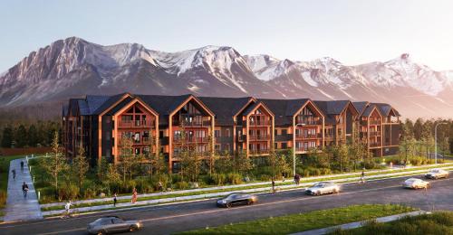 a building with cars driving down a road with mountains in the background at Brand New Mountain Retreat! in Canmore