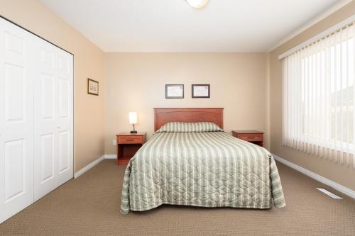 a bedroom with a bed and two night stands and a window at Paradise Canyon Golf Resort - Luxury Condo U399 in Lethbridge
