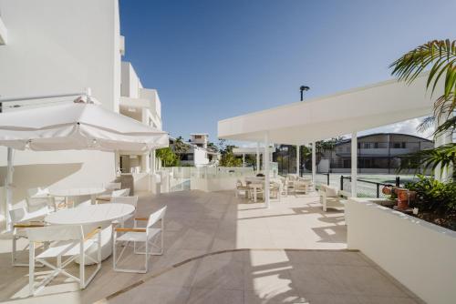 an outdoor patio with tables and chairs and umbrellas at Bay Royal Apartments in Byron Bay