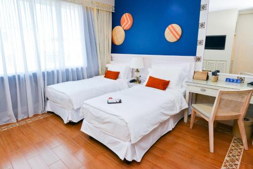 a hotel room with two beds and a desk at Sojourn Spa Hotel Melaka in Melaka