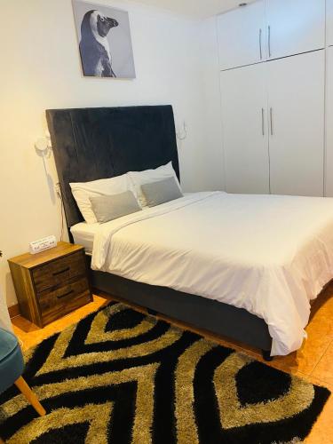 a bedroom with a bed with a black headboard and a rug at Khayelihle Guest house in Benoni