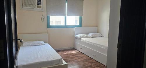a small room with two beds and a window at UrduEnglishFamilyApartmen in Sharjah