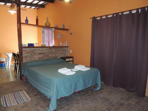 1 dormitorio con 1 cama con toallas en Apart-Cabañas De La Plaza en San Marcos Sierras