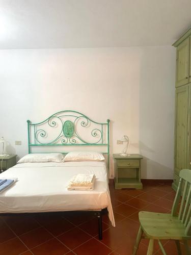 a bedroom with a bed and a green chair at Casa Terrazza sul Golfo in Cannigione