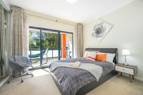 a bedroom with a bed and a chair and a window at Comfy 2-bedroom 2-balcony apartment Close to CBD, Train and Metro easy reach in Sydney