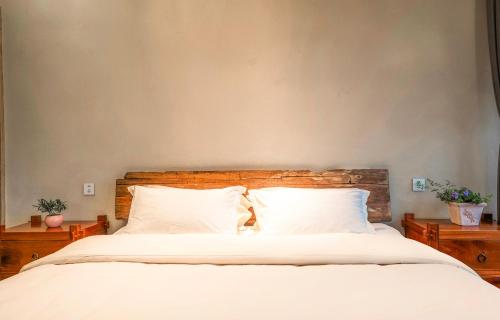 a bedroom with a bed with white sheets and pillows at Xianxiuju Garden Courtyard B&B in Fenghuang