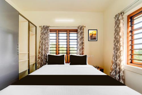 a bedroom with a large bed and a window at Super Townhouse Kalady Near Airport in Cochin