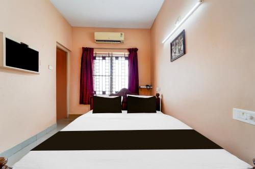 a bedroom with a large white bed with a window at Super Hotel O Anna Nagar Madurai in Madurai