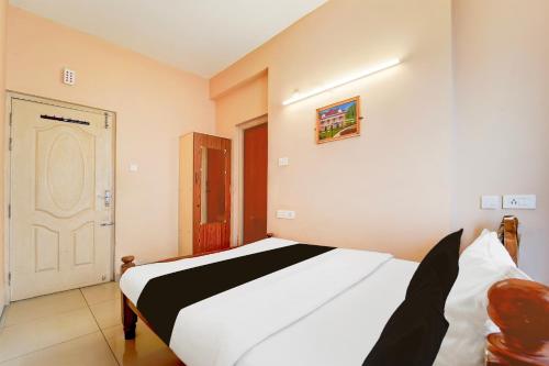 a bedroom with a white bed with a black and white blanket at Super Hotel O Anna Nagar Madurai in Madurai