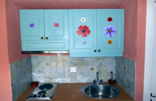 a kitchen with blue cabinets with flowers on them at Polytropon Apartments in Kástron