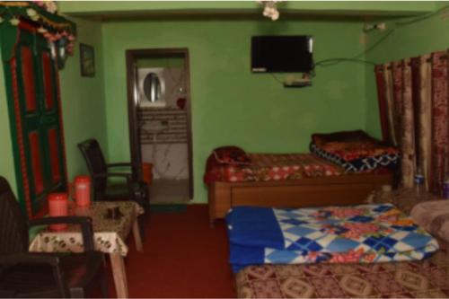 比姆塔尔Jai Somwari Baba Home Stay的一间卧室，墙上有一张床和一台电视