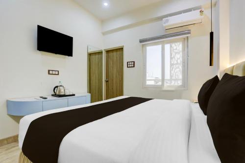 ein weißes Schlafzimmer mit einem Bett und einem Fernseher in der Unterkunft Collection O George Town in Colonelganj