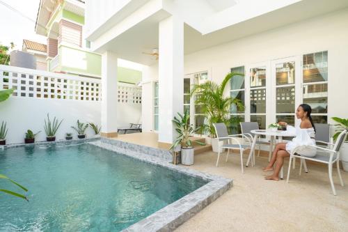 a woman sitting on a chair next to a swimming pool at Happiness Pool villa Phuket Patong 154 in Patong Beach