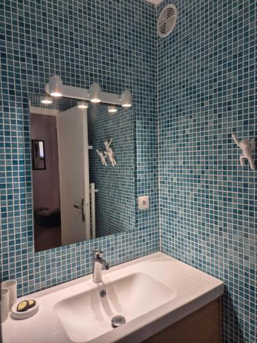 La salle de bains est pourvue d'un lavabo, d'un miroir et de carrelage bleu. dans l'établissement La Plume du Ventoux suite 506, à Mollans-sur-Ouvèze