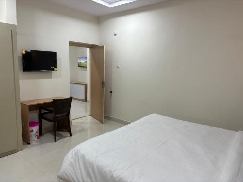 a bedroom with a bed and a desk and a television at Vizag Comforts in Visakhapatnam