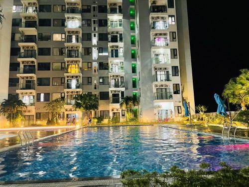a swimming pool in front of tall buildings at night at Châu Giang Homestay, Nera Garden Huế in Thôn Văn Dương