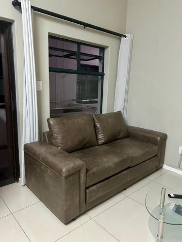 a brown couch in a living room with a window at Meridian Suite Apartments in Umhlanga Ridge in Durban