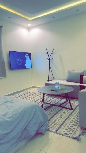 ein Wohnzimmer mit einem Tisch, einem Sofa und einem TV in der Unterkunft استديو هادئ النرجس in Quai