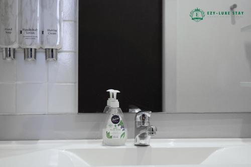 a bathroom sink with a bottle of soap and a mirror at Famous Hotel Melbourne CBD in Melbourne