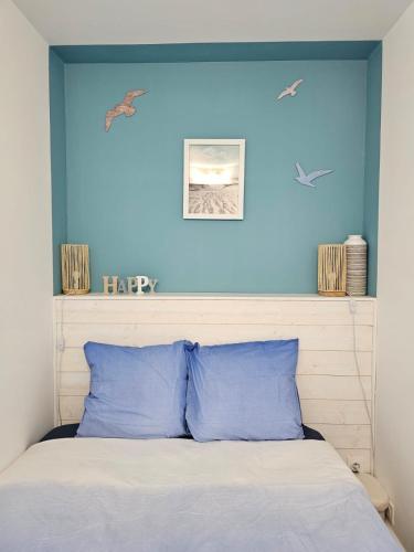 - une chambre dotée d'un mur bleu et d'un lit avec des oreillers bleus dans l'établissement T2 climatisé magnifique vue port, à Gruissan