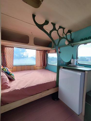 Cette petite chambre comprend un lit et un arbre sur le mur. dans l'établissement Camping Les Ronds Duval face aux îles anglo-normandes, à Les Moitiers-dʼAllonne