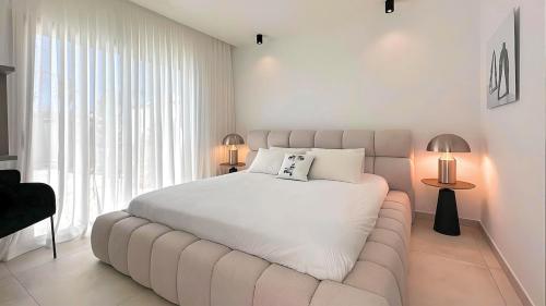 - une chambre blanche avec un grand lit et une grande fenêtre dans l'établissement La Maison de La Plage, au Grau-dʼAgde