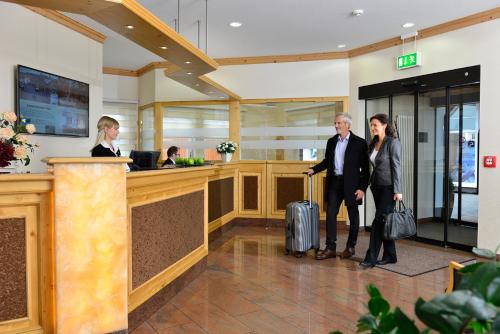 a man and woman standing in a lobby with luggage at Ringhotel Weißer Hirsch in Wernigerode