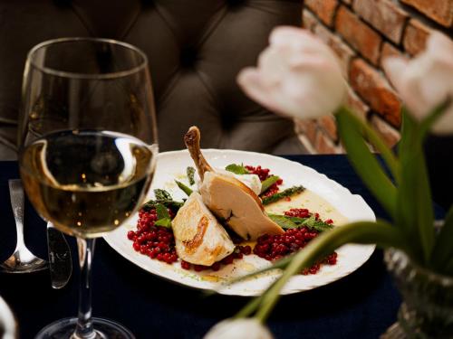 a plate of food on a table with a glass of wine at Hotel Scout in Częstochowa