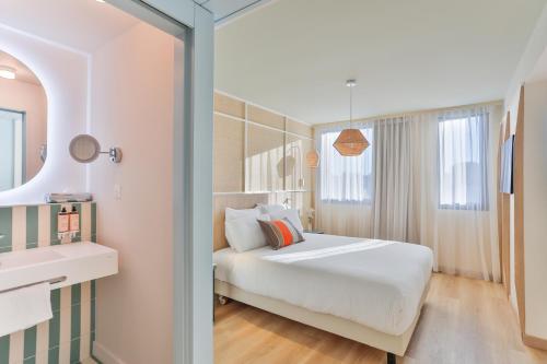 a bedroom with a bed and a sink and a mirror at Mercure Président Biarritz Plage in Biarritz