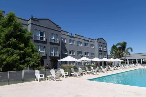 a hotel with chairs and umbrellas next to a swimming pool at Howard Johnson Hotel & Resort Funes in Funes
