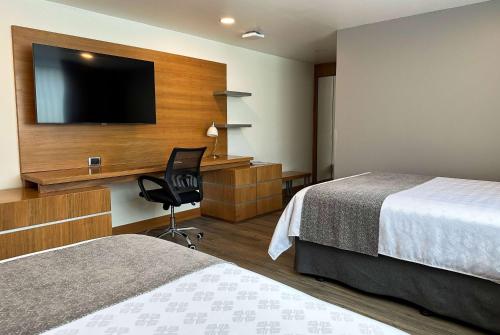 a hotel room with two beds and a desk with a television at Wyndham Garden Quito in Quito