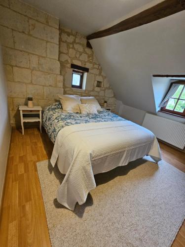 une chambre avec un grand lit avec un mur en pierre dans l'établissement Au pied du Lavoir chambre Germaine, à Grézillé