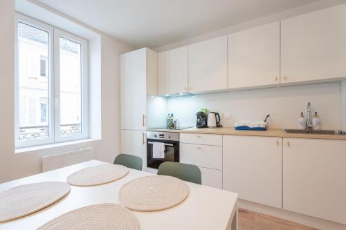 une cuisine avec des armoires blanches et une table et des chaises dans l'établissement Very nice apartment for 4 people, free parking at Macon Park, à Mulhouse