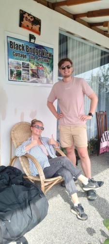 a man standing next to a woman sitting in a chair at Ella Black Bridge View Cottage Sri Lanka in Ella
