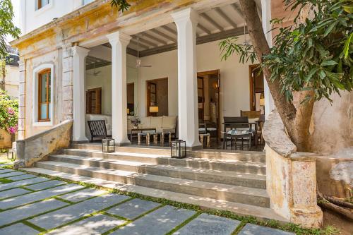 an old house with stairs leading to a porch at La Villa in Puducherry