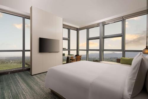a bedroom with a large white bed and windows at Doubletree By Hilton Guang'An in Guang'an