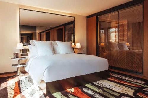 a bedroom with a large white bed and a large window at Hotel SAX Paris, LXR Hotels & Resorts in Paris