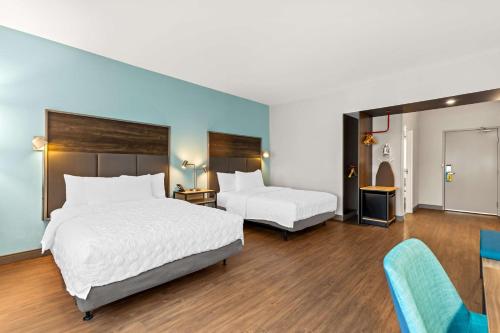 a hotel room with two beds and a chair at Tru By Hilton Aloha Beaverton in Beaverton