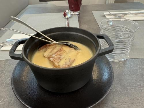 a black pot of soup on a plate on a table at La Table de Gustave in Ornans